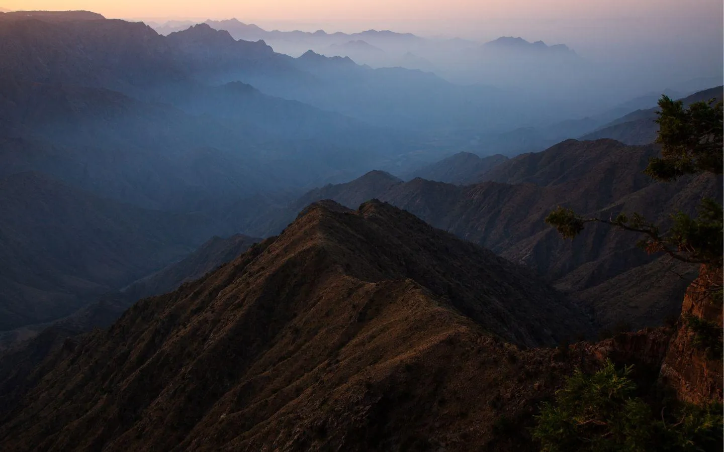 Sunrise over misty mountain peaks in Abha